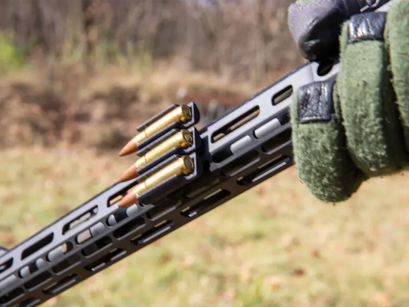 Hunter in field accessing extra rounds from M-LOK mounted ammo carrier during shooting session